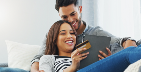 couple smiling at tablet and credit card
