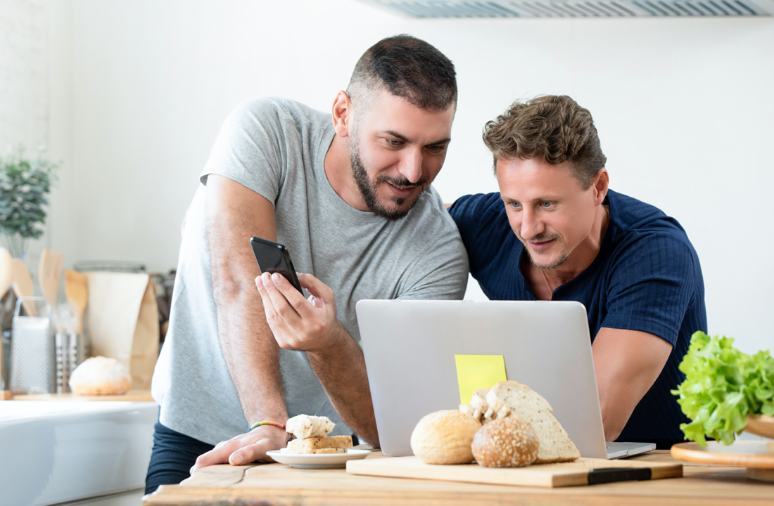 two men looking at laptop on counter